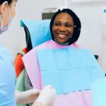 A smiling woman receives dental check-up from a practitioner in modern clinic.